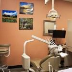 Dental examination room with dental chair, overhead equipment, and peach-colored walls